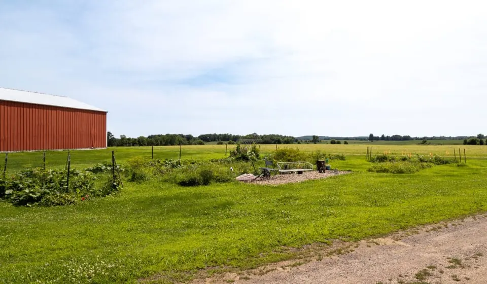Vegetable garden beside a red barn and open fields