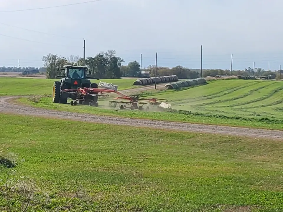Tractor and farm machinery working in a freshly cut hay field