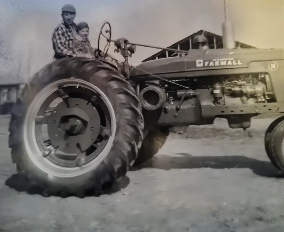 An archival family photograph of a farmer on a tractor at Longview Farm