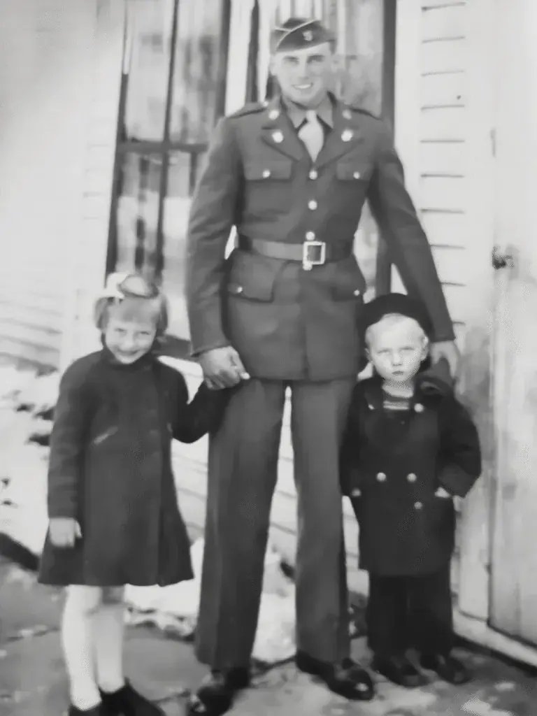 Black and white family photograph of a man in uniform standing with two children