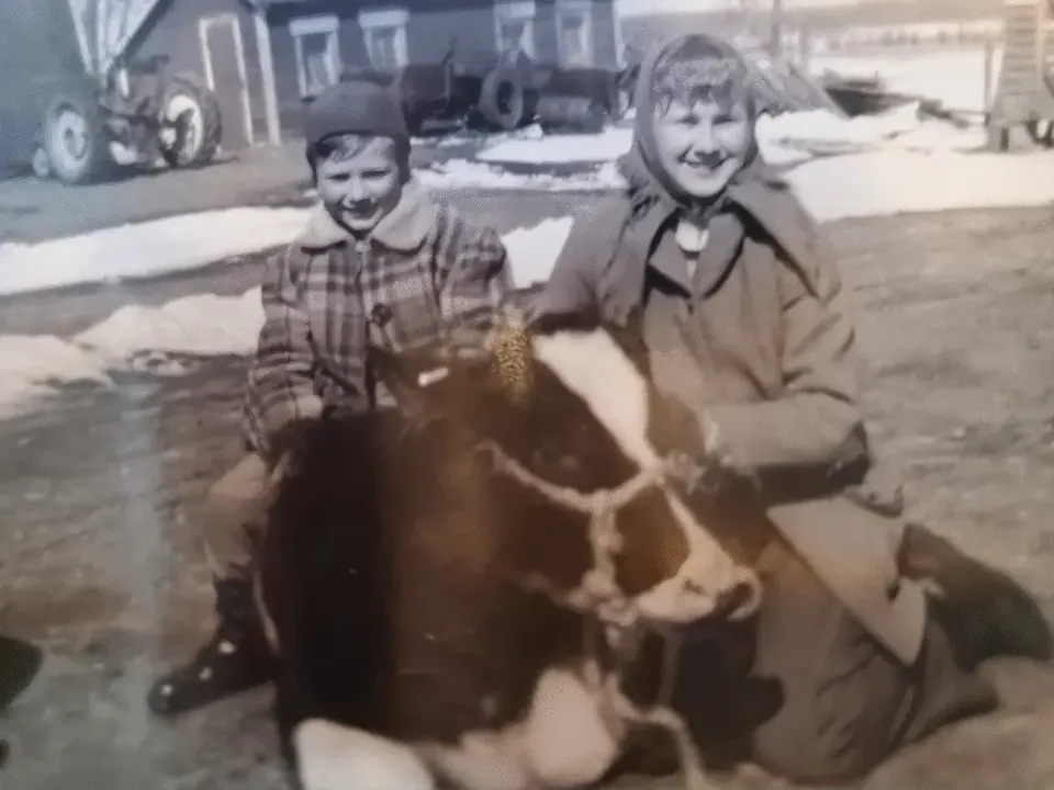 Black and white photograph of two children beside a cow