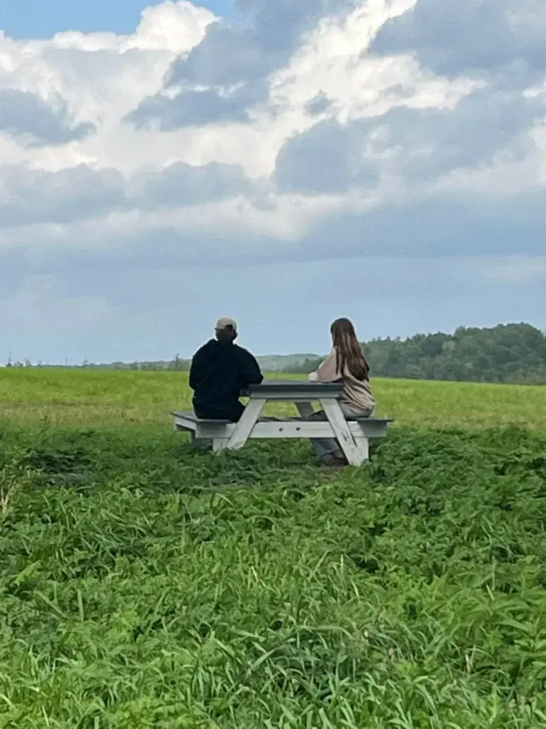 Two people sitting at a picnic table overlooking the fields